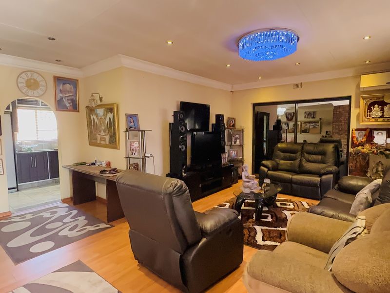 Spacious living room featuring laminate flooring, recessed lighting, and an air conditioning unit, with an arched entryway leading to the kitchen area.