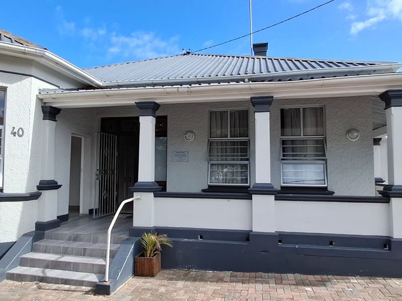 Front elevation of a guest house featuring a covered veranda, tiled entrance steps, and a paved driveway area.