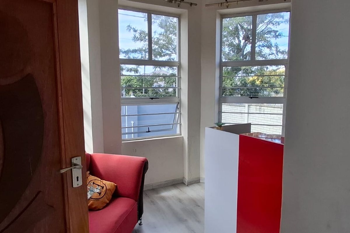 A bright living area featuring laminate flooring and louvered windows, providing natural light and a view of the exterior surroundings.