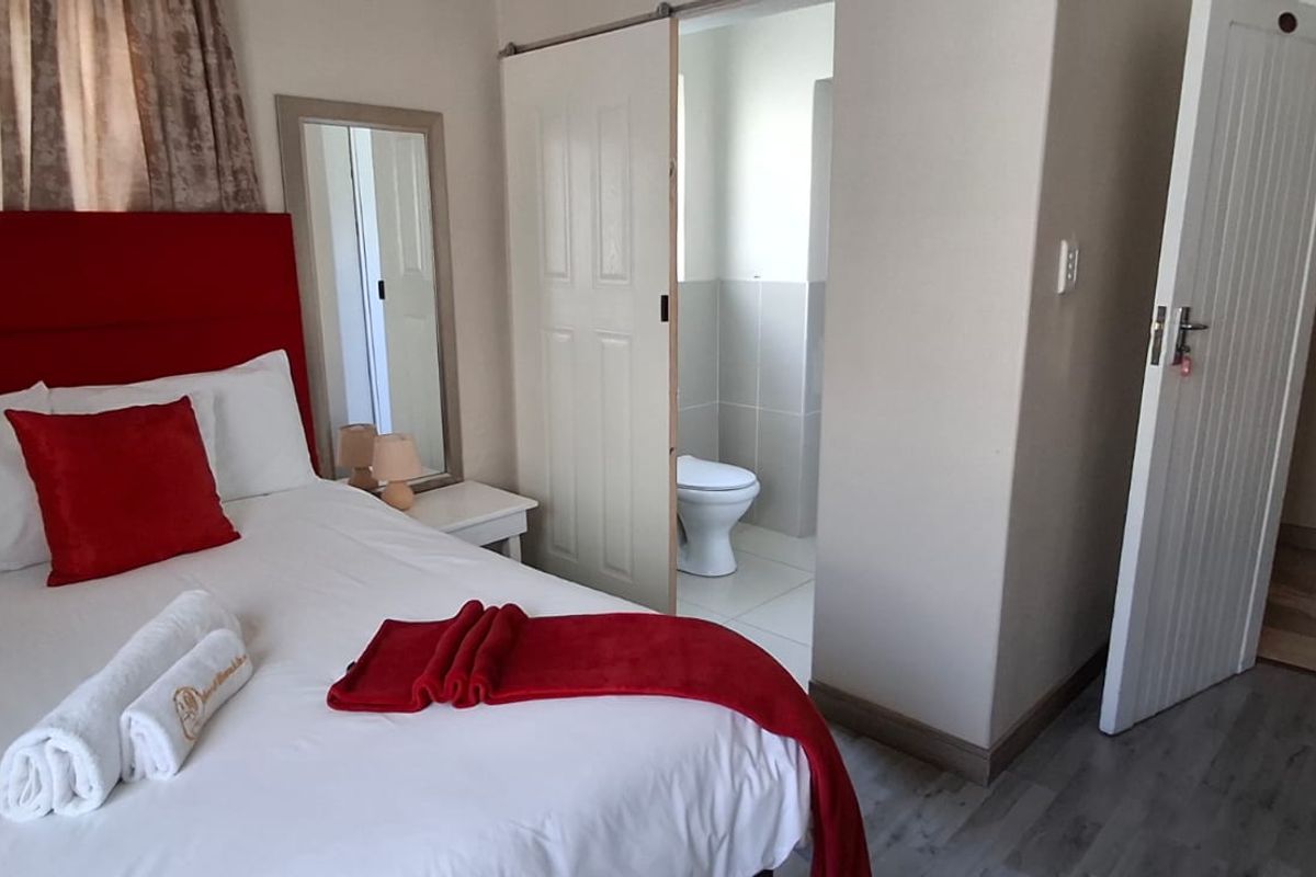 A bedroom featuring a sliding door leading to an en-suite bathroom, with neutral wall finishes and tiled flooring throughout.