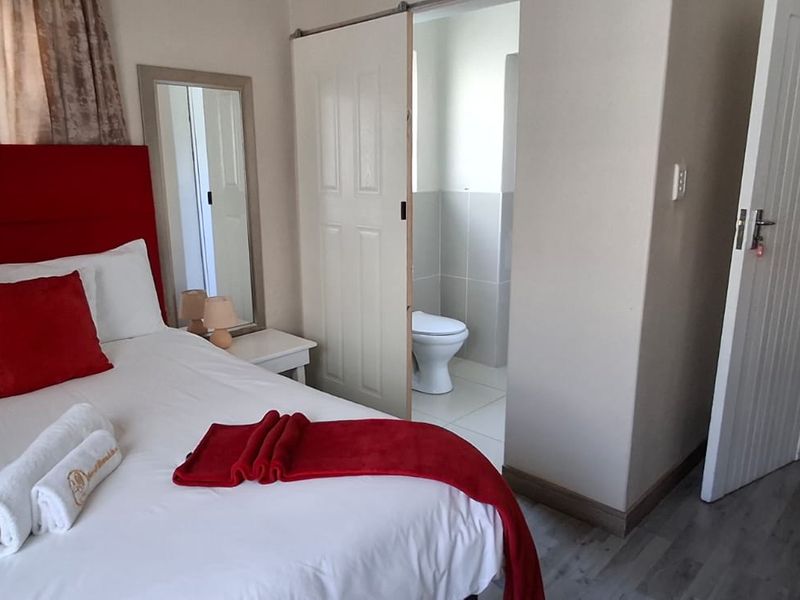 A bedroom featuring a sliding door leading to an en-suite bathroom, with neutral wall finishes and tiled flooring throughout.