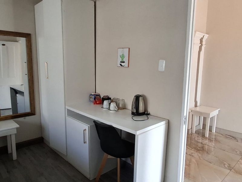 A bedroom featuring built-in cabinetry, laminate flooring, and an adjoining tiled area, providing functional guest accommodation space.
