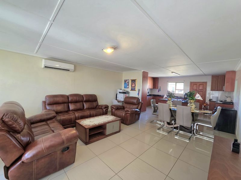 Spacious open-plan living and dining area featuring tiled flooring, a split-system air conditioner, and an integrated kitchen with wooden cabinetry.