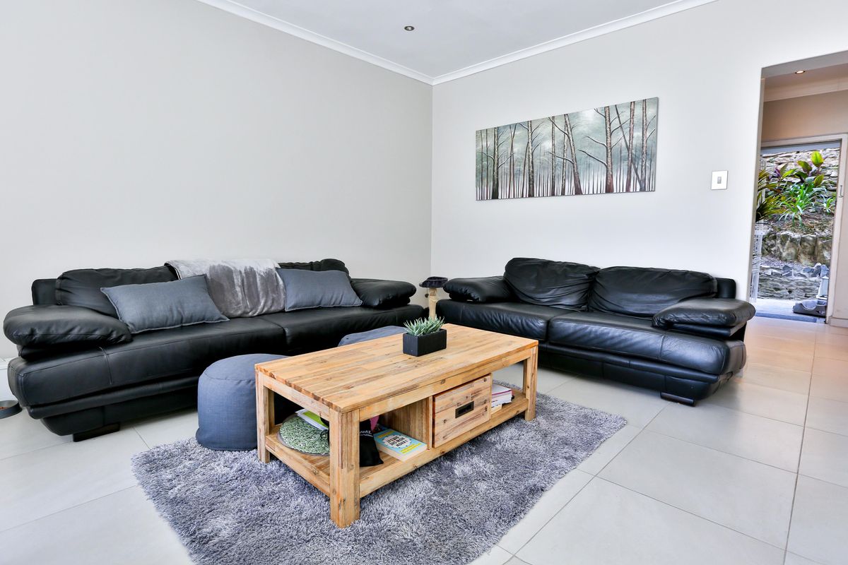 A bright living room featuring neutral tiled flooring, recessed downlighting, and coved ceiling details, offering a clean and functional space.