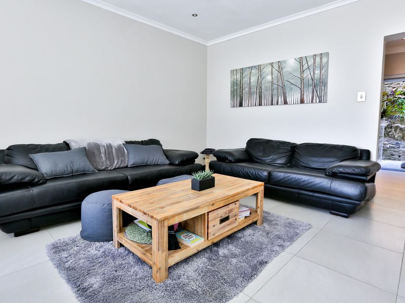A bright living room featuring neutral tiled flooring, recessed downlighting, and coved ceiling details, offering a clean and functional space.
