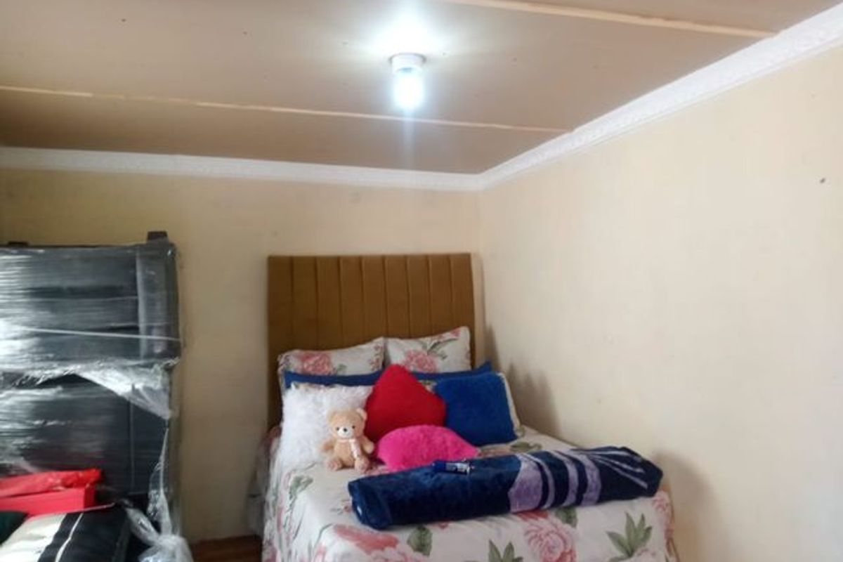 A bedroom featuring laminate flooring and ceiling cornicing, requiring cosmetic updates to the walls and ceiling finish.