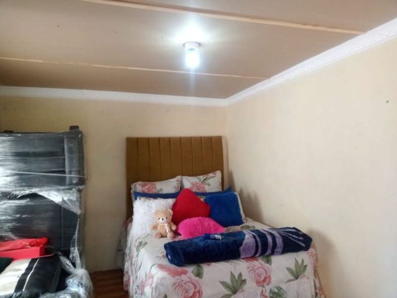 A bedroom featuring laminate flooring and ceiling cornicing, requiring cosmetic updates to the walls and ceiling finish.