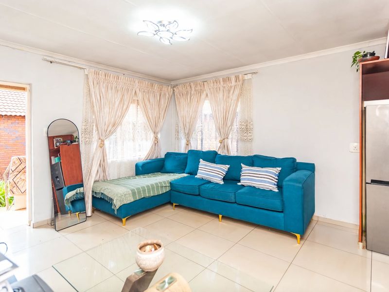 A bright living room featuring tiled flooring and natural light, providing a comfortable and functional space for relaxation.