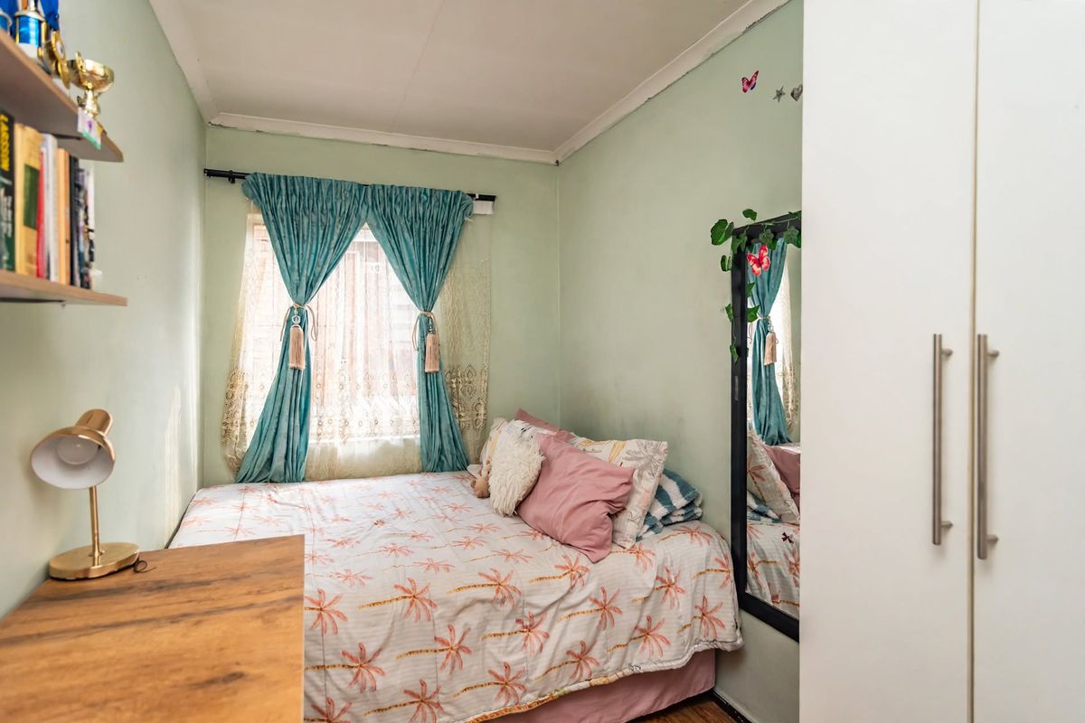 A compact bedroom featuring a built-in wardrobe and a window with natural light, offering a functional space for rest.