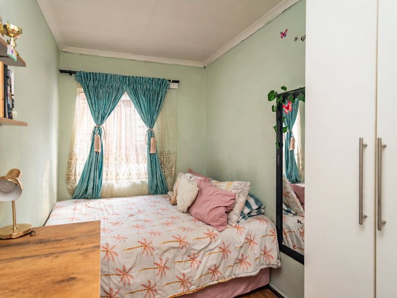 A compact bedroom featuring a built-in wardrobe and a window with natural light, offering a functional space for rest.