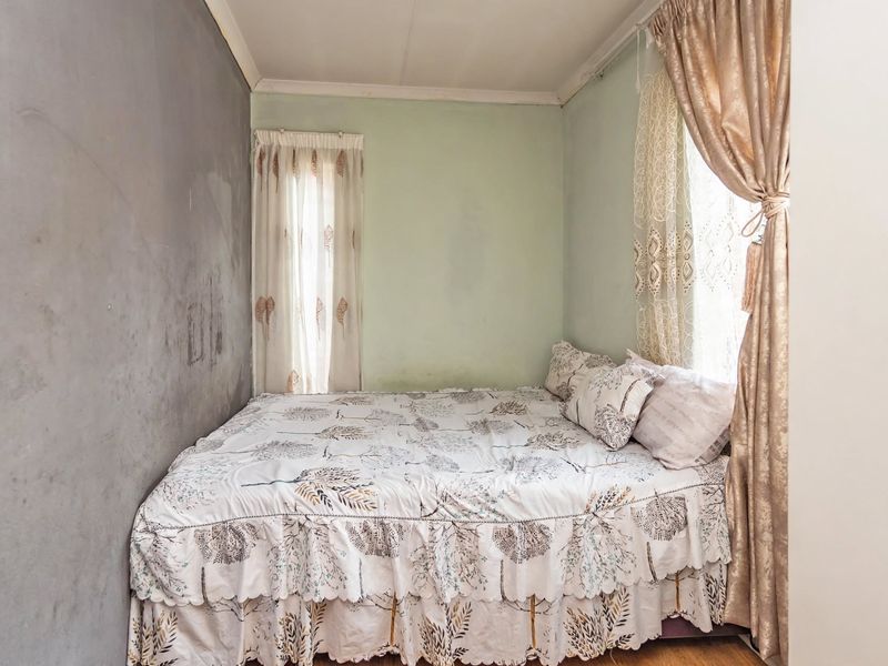 A compact bedroom featuring a dual-tone wall finish and dual window treatments.