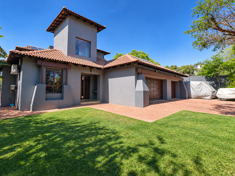 A well-maintained modern house featuring a terracotta tiled roof, grey exterior walls, a spacious paved driveway, and an integrated double garage.