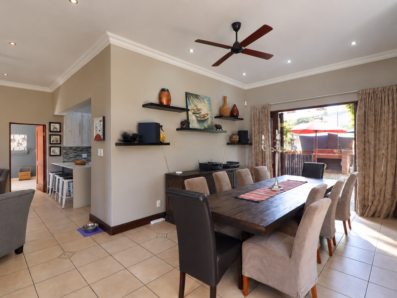 Spacious open-plan dining and kitchen area featuring tiled floors, recessed lighting, and seamless access to the outdoor patio through sliding glass doors.
