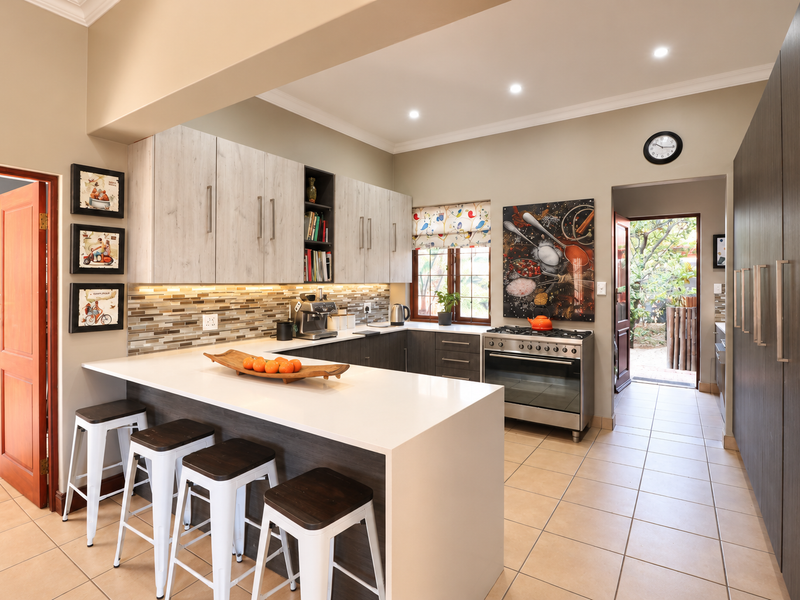 Modern kitchen featuring quartz countertops, mosaic tile backsplash, built-in cabinetry, and a gas stove, with direct access to an outdoor area.