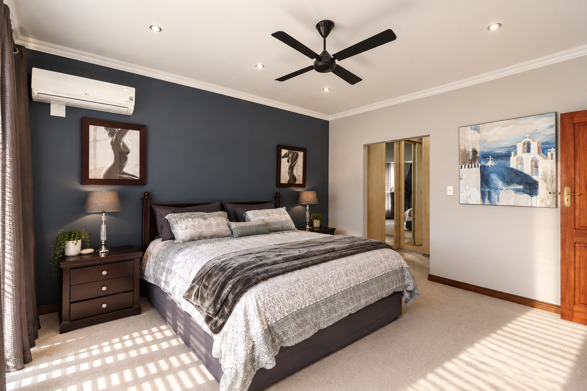 A well-maintained bedroom featuring a dark accent wall, split-system air conditioning, ceiling fan, recessed lighting, and a built-in wardrobe with mirrored doors.