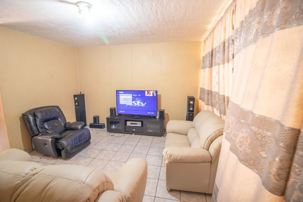 A living room featuring tiled flooring and a textured ceiling, providing a functional space for relaxation and entertainment.