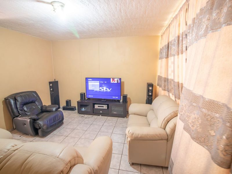 A living room featuring tiled flooring and a textured ceiling, providing a functional space for relaxation and entertainment.