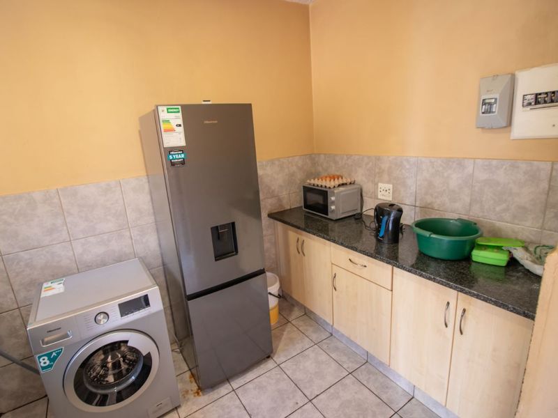 A functional laundry area featuring laminate cabinetry, granite countertops, tiled backsplash, and tiled flooring, equipped with space for major appliances.