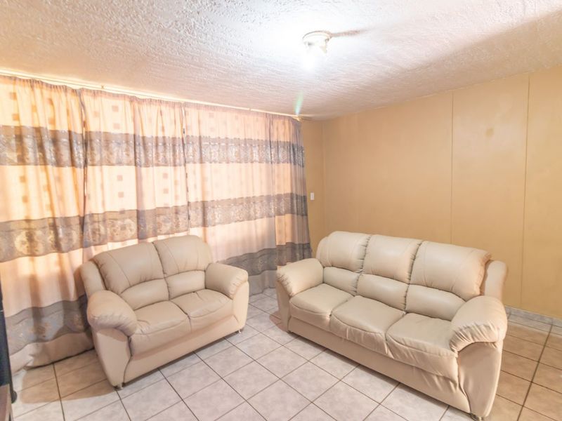A living room featuring tiled flooring and a textured ceiling, offering a functional space ready for modern updates and cosmetic improvements.