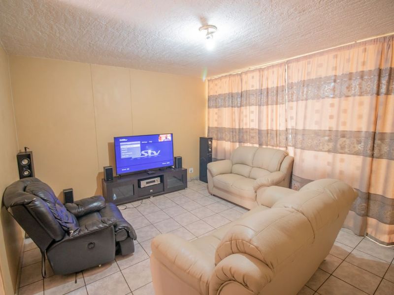 A living room featuring tiled flooring and a textured ceiling, providing a functional space for relaxation.