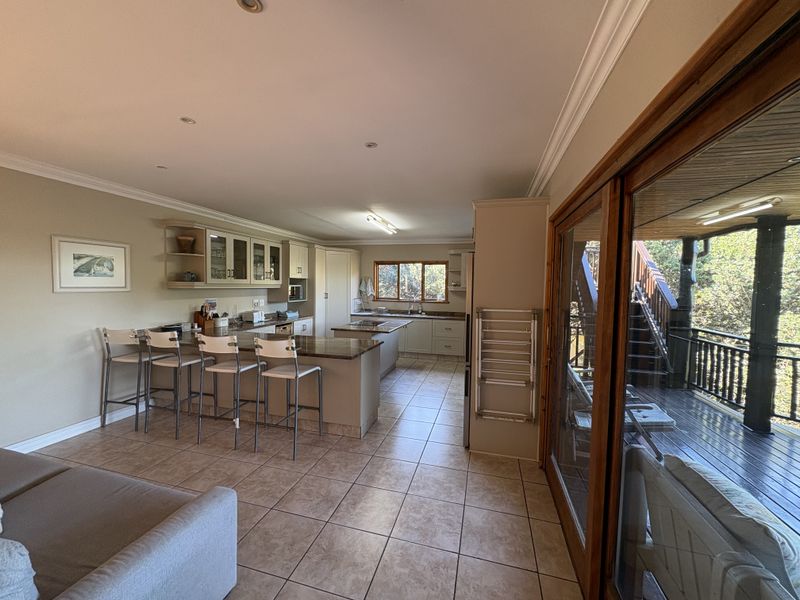 Spacious open-plan kitchen and living area featuring granite countertops, ample cabinetry, and large sliding doors leading to an outdoor deck.