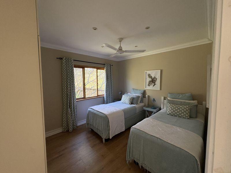 A well-maintained bedroom featuring laminate flooring, recessed downlights, a ceiling fan, and built-in storage with a view of the outdoors.