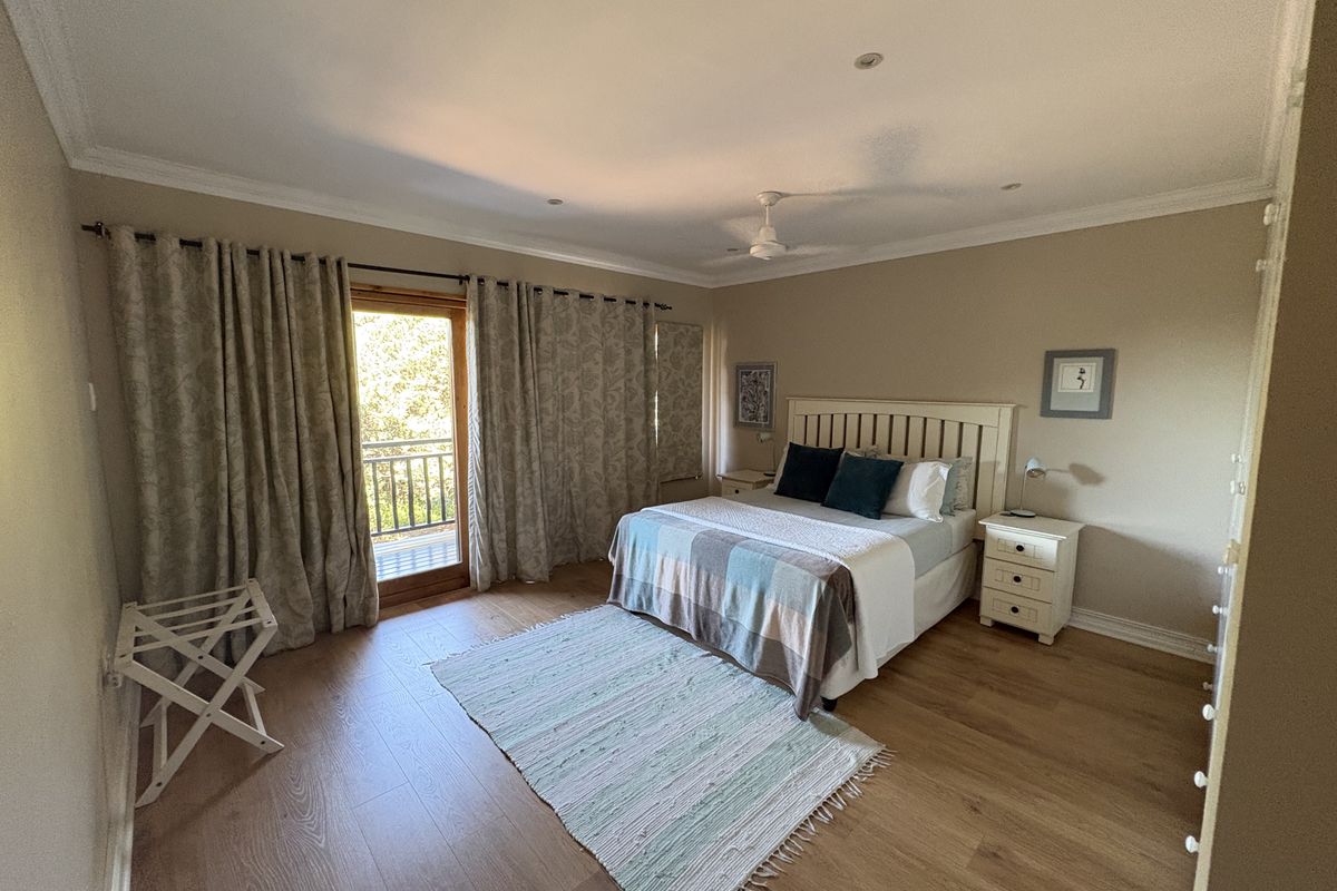 Spacious bedroom featuring laminate flooring, a ceiling fan, and direct access to a private balcony through a glass-paneled door.
