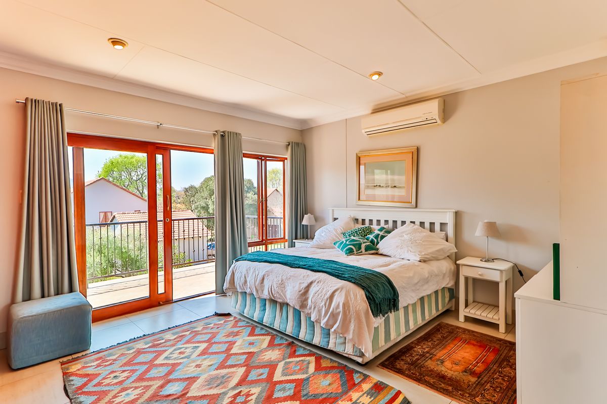 Spacious bedroom featuring tiled flooring, an integrated air conditioning unit, and large sliding glass doors providing direct access to a private balcony.