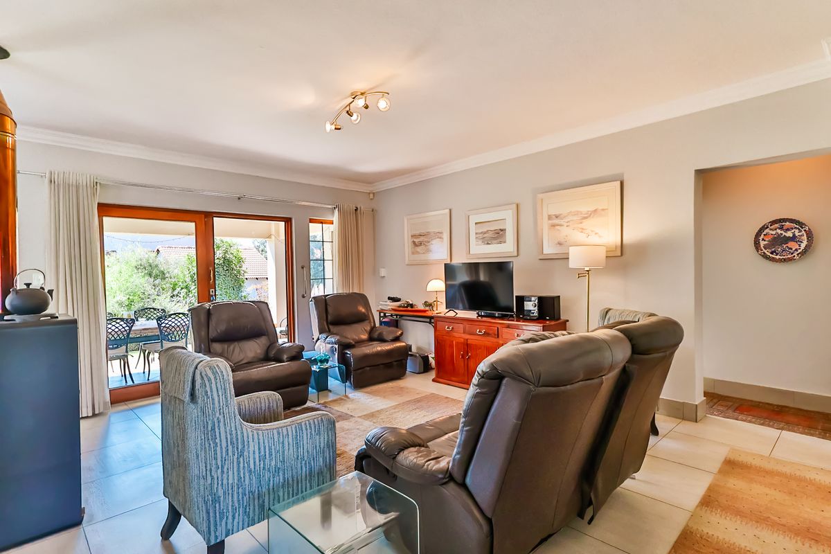 Spacious living room featuring tiled flooring, cove molding, and large sliding glass doors that provide natural light and access to the outdoor patio area.