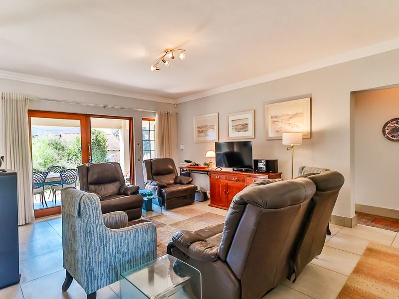 Spacious living room featuring tiled flooring, cove molding, and large sliding glass doors that provide natural light and access to the outdoor patio area.