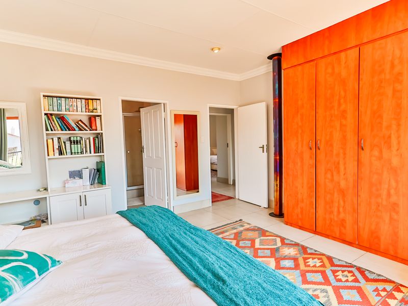 Spacious bedroom featuring built-in wooden cupboards, tiled flooring, and direct access to an en-suite bathroom.