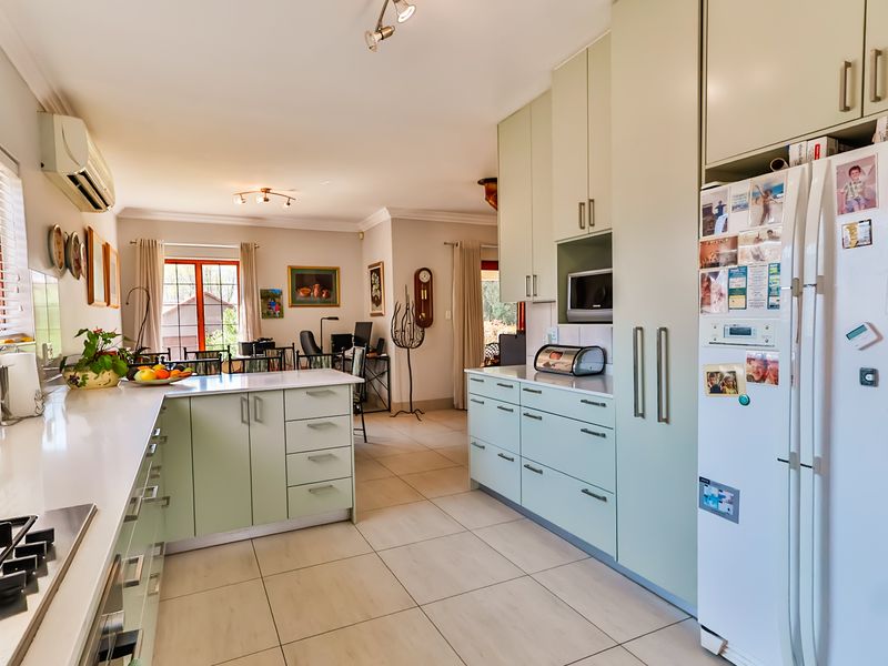 Spacious open-plan kitchen and living area featuring light green cabinetry, stone countertops, tiled flooring, and a built-in gas cooktop.