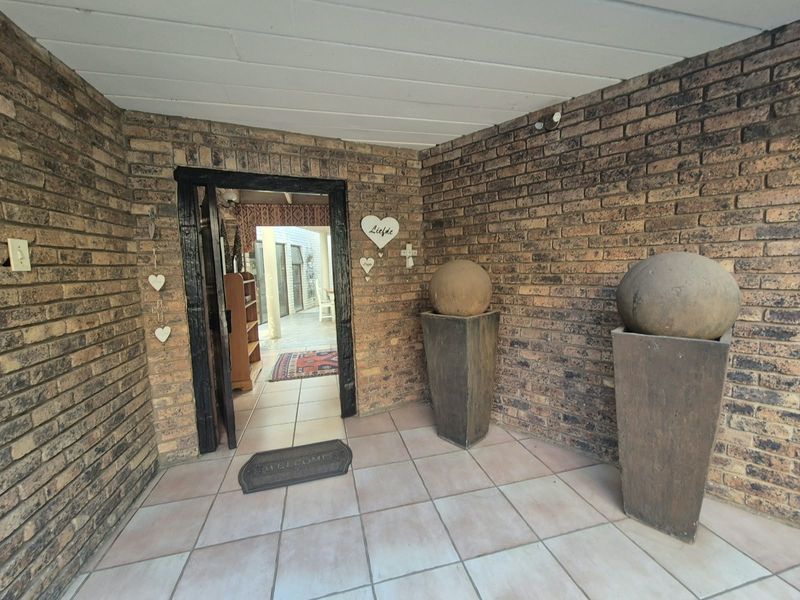 A covered entrance area featuring exposed brick walls, tiled flooring, and a painted timber ceiling, providing a welcoming transition into the home.