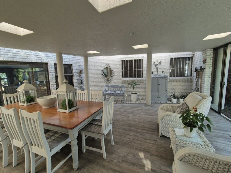 A spacious covered patio featuring exposed brick walls, skylights, recessed lighting, and wood-look flooring, providing a bright and inviting outdoor entertainment area.