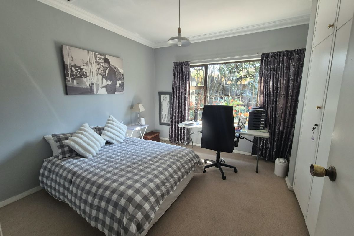 A functional bedroom featuring built-in cupboards, neutral wall tones, and carpeted flooring, offering a comfortable space with natural light.