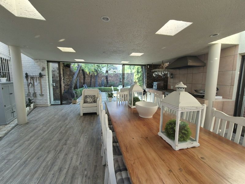 Spacious covered patio featuring a built-in braai area, recessed lighting, and large sliding doors opening to a private garden.