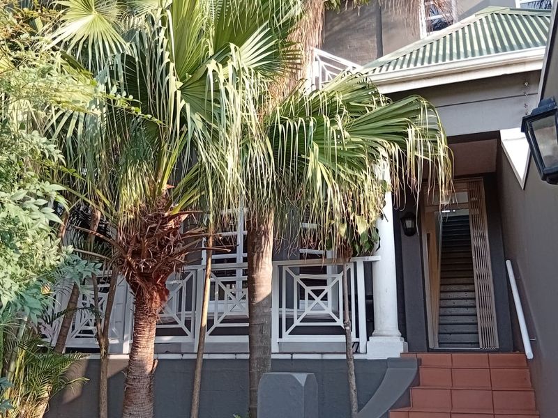 Front entrance of the townhouse featuring a tiled staircase leading to a covered porch with white balustrades and a secure entrance.