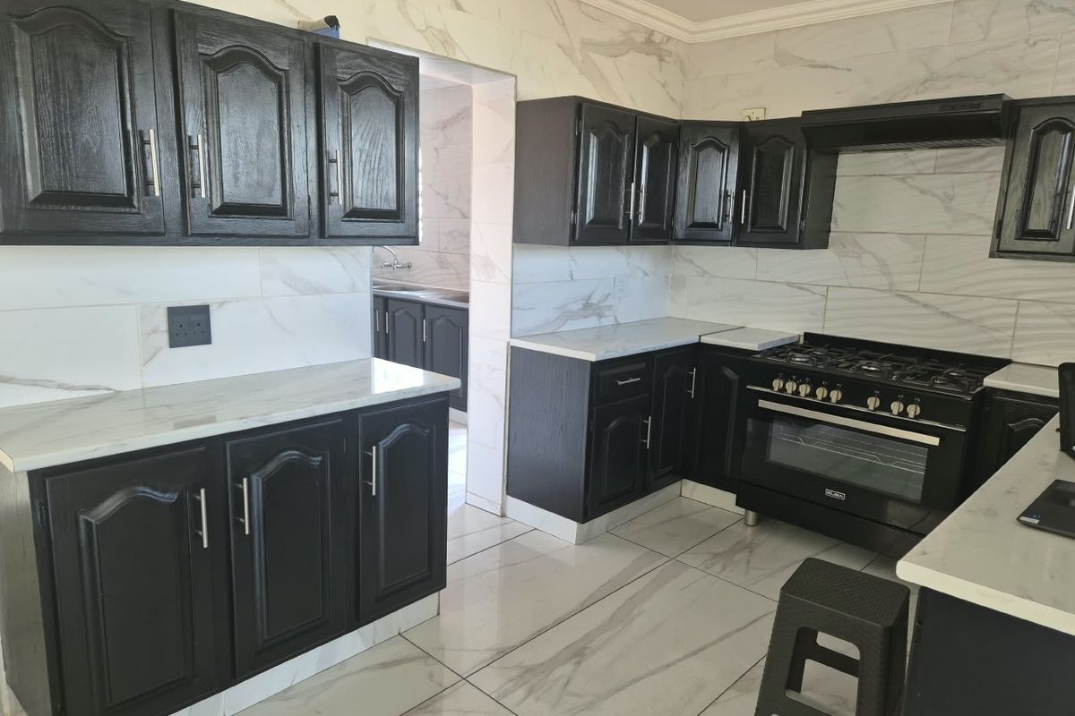 Modern kitchen featuring dark cabinetry, marble-look countertops, tiled flooring, and a built-in gas stove with an extractor fan.