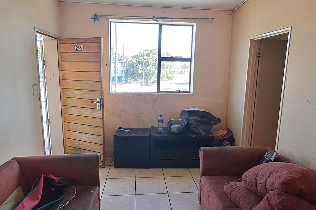 A living room area featuring tiled flooring and a window, requiring cosmetic updates to improve the overall aesthetic and condition of the space.