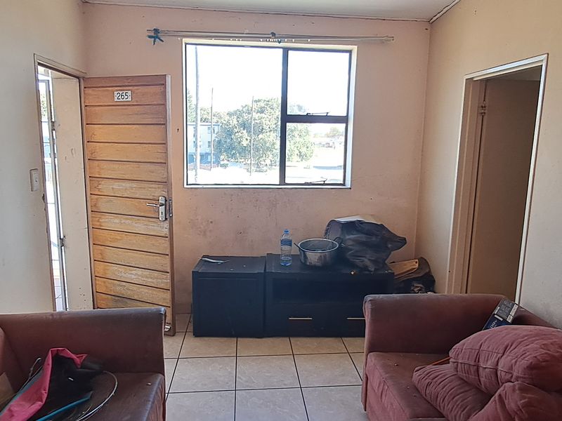 A living room area featuring tiled flooring and a window, requiring cosmetic updates to improve the overall aesthetic and condition of the space.