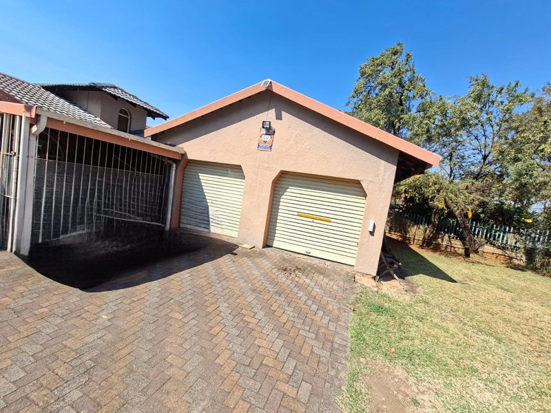 Exterior view of a double garage featuring roll-up doors, a paved driveway, and adjacent lawn area.