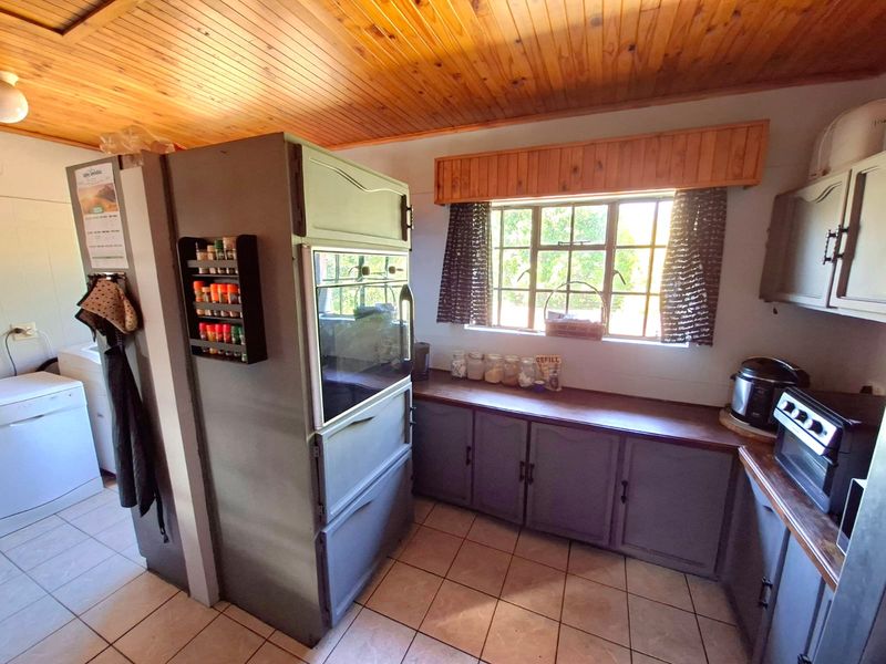A functional kitchen featuring built-in cabinetry, timber ceiling, tiled flooring, and a built-in oven, offering a practical layout with natural light.