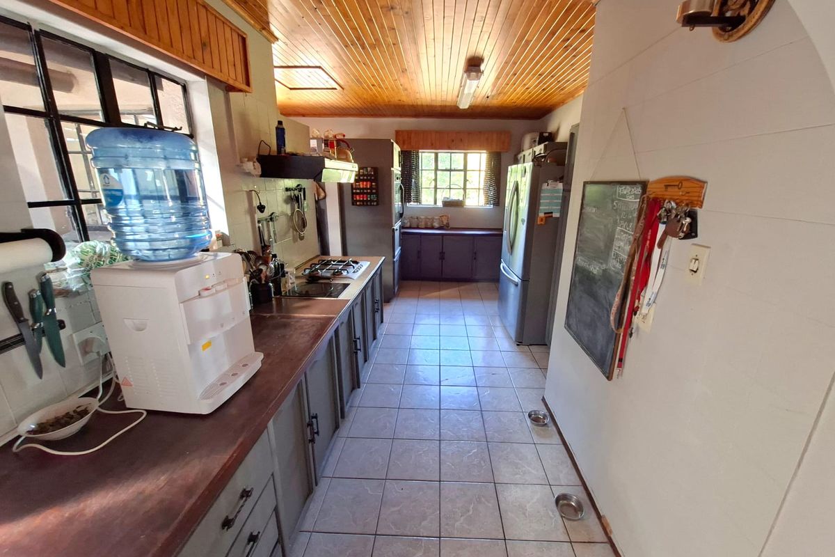 A functional kitchen featuring built-in cabinetry, a gas hob, extractor fan, and tiled flooring, finished with a timber-clad ceiling.