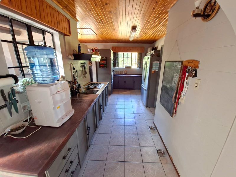 A functional kitchen featuring built-in cabinetry, a gas hob, extractor fan, and tiled flooring, finished with a timber-clad ceiling.