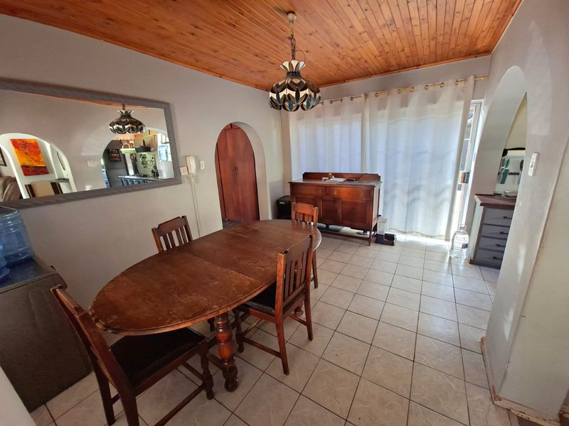 Dining room featuring a timber tongue and groove ceiling, ceramic tiled flooring, and arched architectural details leading to adjacent living spaces.