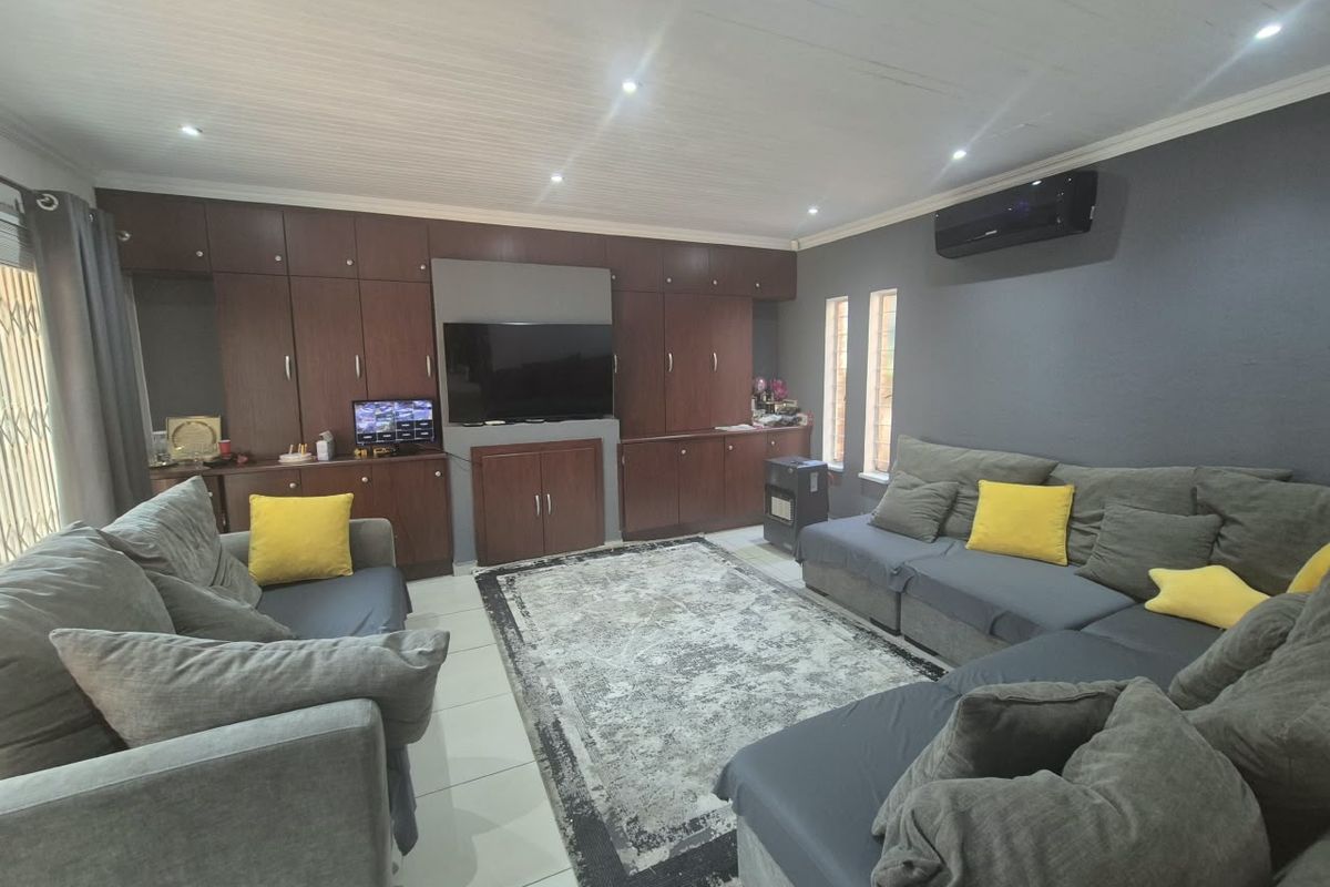 A comfortable living room featuring extensive built-in dark wood cabinetry, tiled flooring, recessed lighting, and a wall-mounted air conditioning unit.