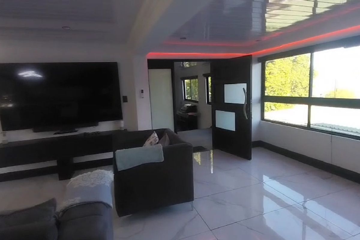 A modern living room featuring polished porcelain tile flooring, recessed ceiling lighting with integrated LED accents, and large windows providing ample natural light.