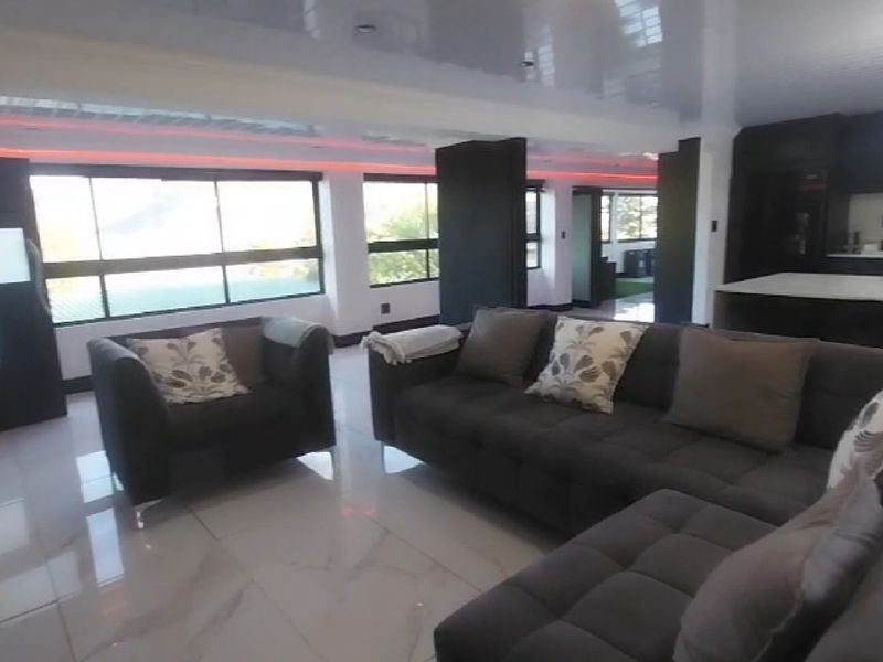 Spacious open-plan living area featuring glossy tiled flooring, modern recessed lighting, and a contemporary kitchen with a central island.