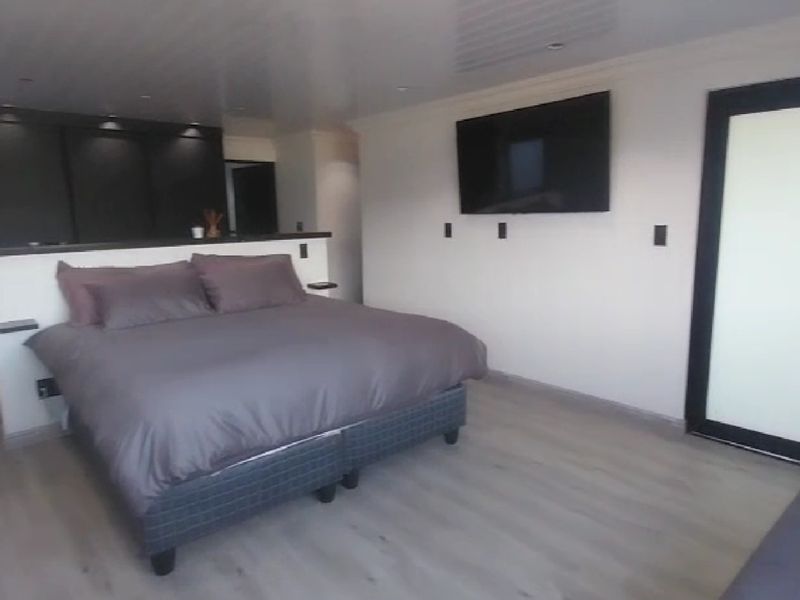 Modern bedroom featuring built-in cupboards, laminate flooring, and a partition wall design with recessed lighting.