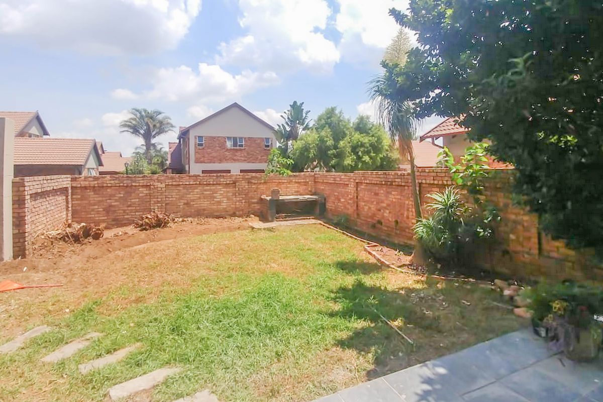 A private rear garden featuring a brick boundary wall, a built-in brick braai, and a paved patio area, offering potential for landscaping.